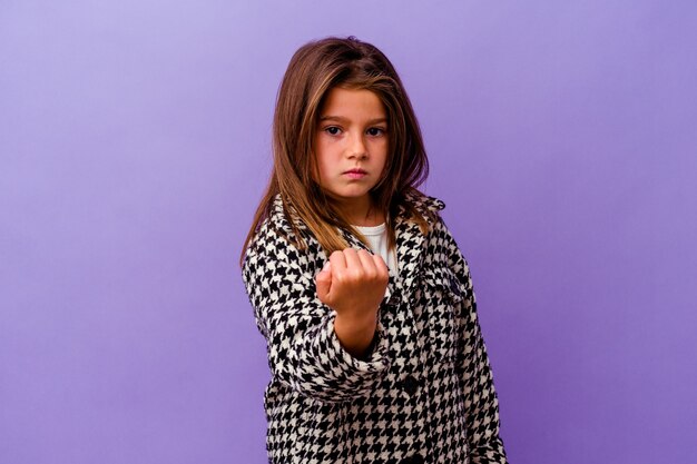 Menina caucasiana isolada no roxo, mostrando o punho para a câmera, expressão facial agressiva.