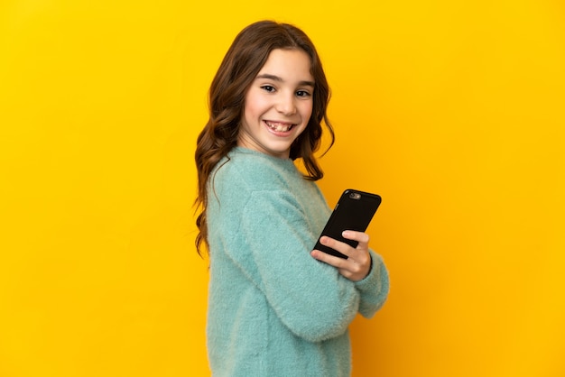 Menina caucasiana isolada segurando um telefone celular e com os braços cruzados