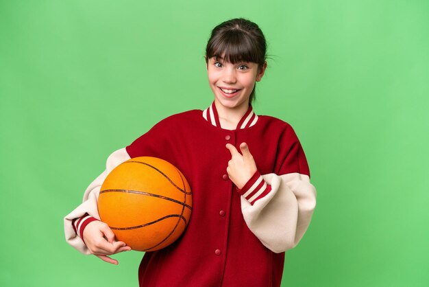 Menina caucasiana jogando basquete sobre fundo isolado com expressão facial de surpresa