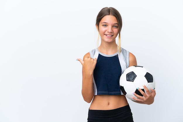 Menina caucasiana jogando futebol isolada no fundo branco, apontando para o lado para apresentar um produto