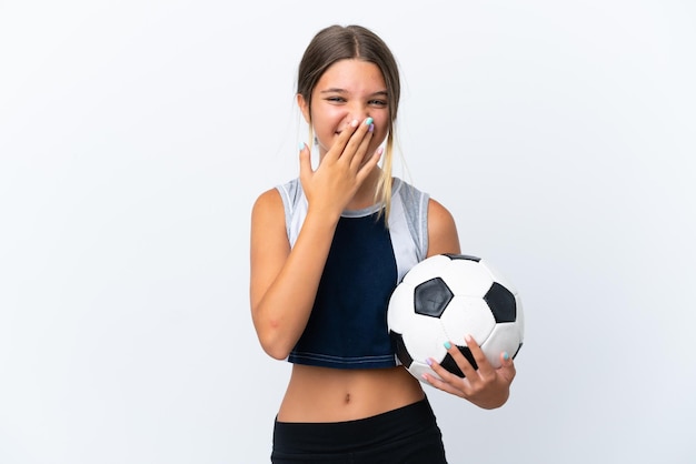 Menina caucasiana jogando futebol isolado no fundo branco feliz e sorridente cobrindo a boca com a mão