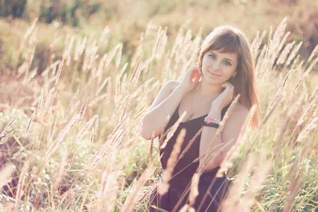 Menina caucasiana, posando no verão ao pôr do sol no campo