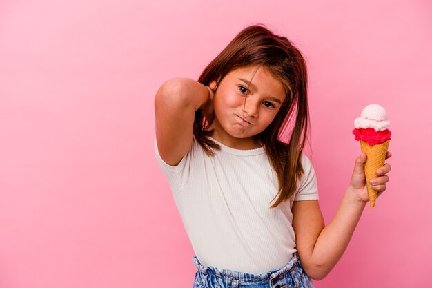 Menina caucasiana segurando sorvete isolado no fundo rosa, tocando a parte de trás da cabeça, pensando e fazendo uma escolha.