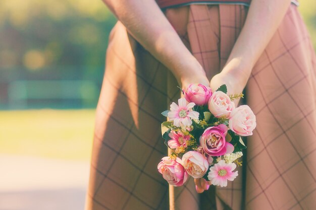 Menina caucasiana segurando um buquê de flores nas mãos no fundo de um verde ensolarado de verão