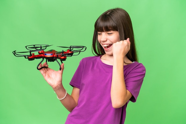 Menina caucasiana segurando um drone sobre fundo isolado comemorando uma vitória