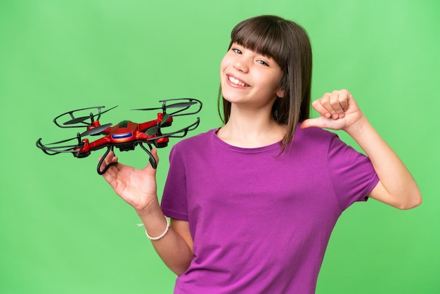 Menina caucasiana segurando um drone sobre fundo isolado orgulhoso e satisfeito