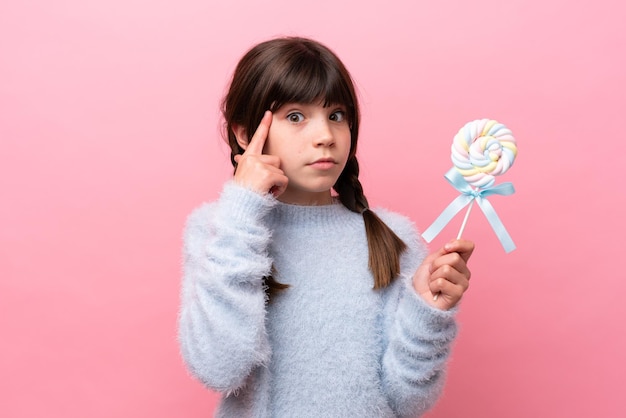 Menina caucasiana segurando um pirulito pensando em uma ideia