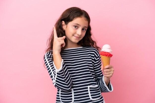 Menina caucasiana segurando um sorvete isolado no fundo rosa apontando uma ótima ideia