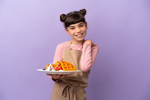 Menina caucasiana segurando waffles isolados na risada roxa