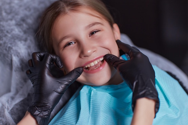 Menina caucasiana sentada na cadeira médica enquanto dentista consertando dentes na clínica odontológica usando instrumentos de ferramentas odontológicas, foto de close-up do rosto. especialista médico profissional.