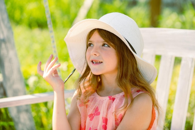 Menina caucasiana usando chapéu de palha em pé ao ar livre Cara de crianças engraçadas