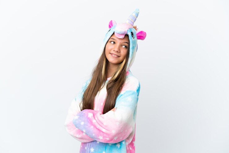 Foto menina caucasiana vestindo pijama de unicórnio isolado no fundo branco com braços cruzados e feliz