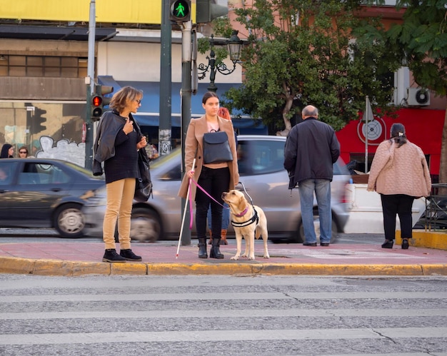 Menina cega atravessa a estrada em uma travessia de pedestres com a ajuda de um cão-guia na Grécia