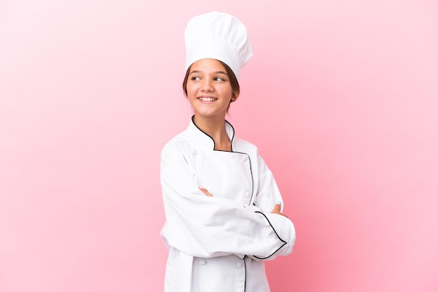 Menina chef caucasiana isolada em um fundo rosa feliz e sorridente