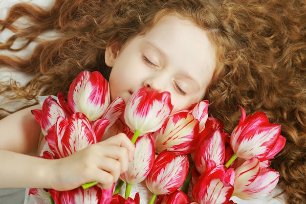 Menina cheirando um buquê de tulipas.