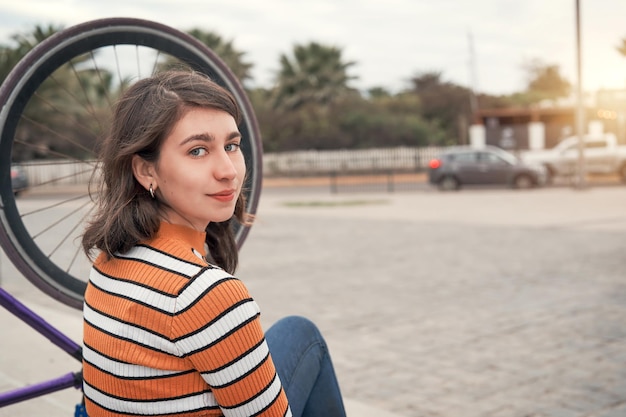 Menina chilena sentada na rua ao lado de sua bicicleta olhando para a câmera e sorrindo