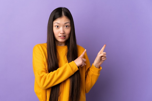 Menina chinesa em cima do roxo assustada e apontando para o lado