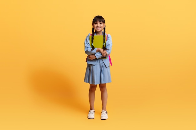Menina chinesa muito pré-adolescente indo para a escola fundo amarelo