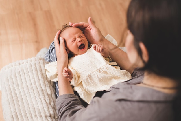 Menina chorando acorda nas mãos da mãe no quarto closeup Mulher com menina infantil Maternidade Infância