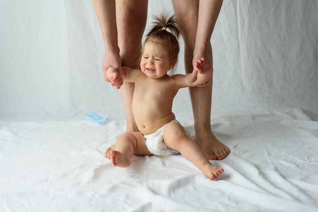 Foto menina chorando. as mãos do pai seguram a criança.