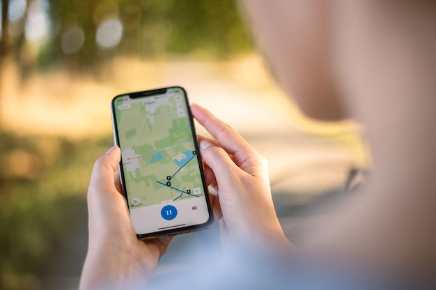 Menina ciclista olha para um mapa em seu telefone e traça uma rota para uma viagem para um navegador GPS