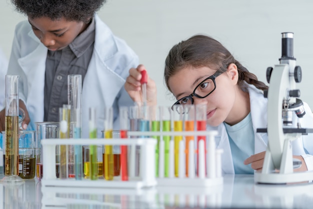 Menina cientista fazendo experimentos químicos em tubo de vidro na sala do laboratório