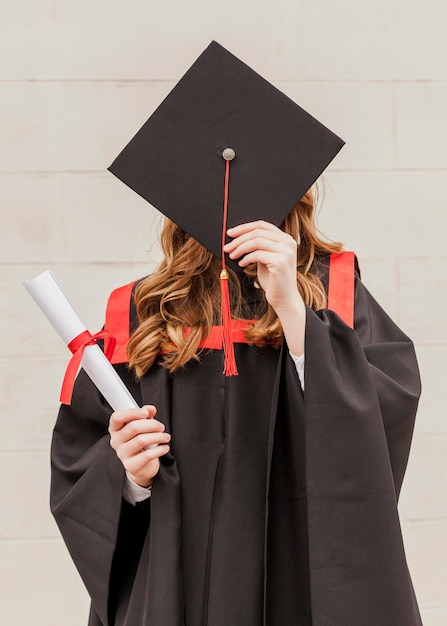 Foto menina, cobrindo o rosto com chapéu de formatura