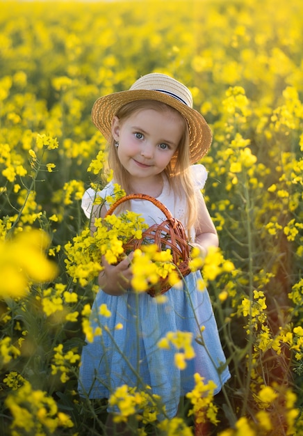 Menina coleta flores, lindo sorriso, campo de colza, natureza no verão