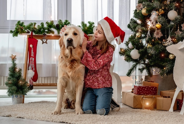 Menina colocando chapéu de Papai Noel no cachorro