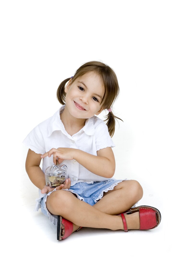 Foto menina colocando dinheiro no cofrinho isolado