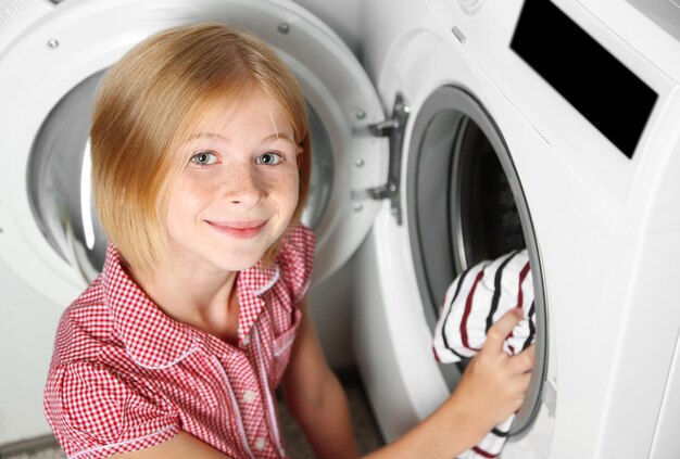 Menina colocando pano na máquina de lavar