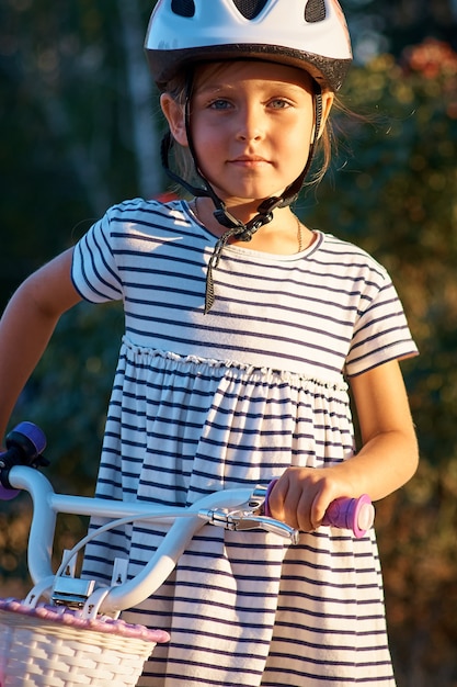 Menina com a bicicleta no parque. Criança na bicicleta