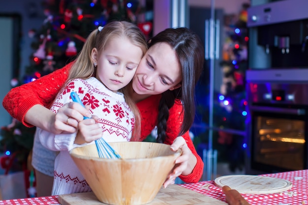 Menina com a jovem mãe assar biscoitos de gengibre de natal juntos