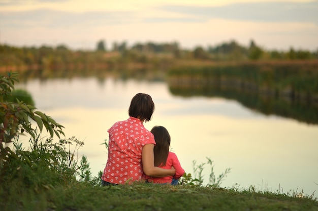 Menina com a mãe perto do lago, vista traseira