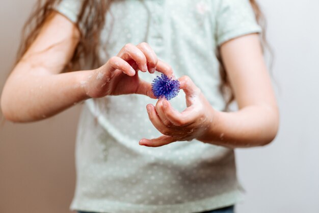 Menina com as mãos no sabão detém um modelo abstrato de vírus.