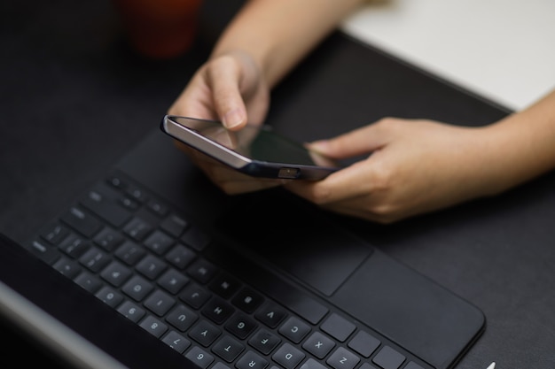 Menina com as mãos tocando no smartphone, jogando, conversando no espaço de trabalho escuro do aplicativo on-line