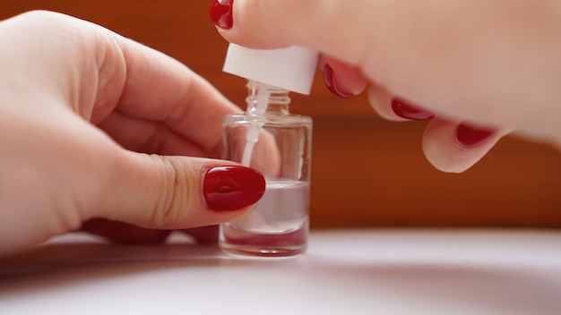 Menina com as unhas pintada de vermelho com um casaco transparente. Preocupe-se com as unhas e com a pele do corpo limpa, macia e lisa.