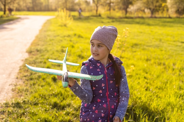 menina com avião de brinquedo nas mãos ao ar livre, parafuso vento-vara do motor de borracha.