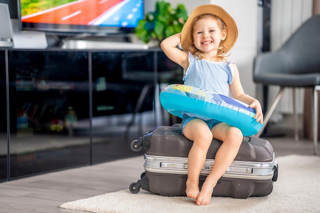 Menina com bagagem de mala e bóia salva-vidas inflável pronta para viajar de férias