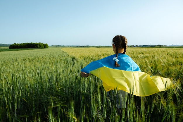 Menina com bandeira ucraniana no campo de trigo menino feliz comemorando o dia da independência