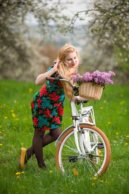 Menina com bicicleta branca vintage com cesta de flores