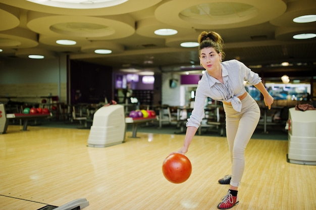 Menina com bola de boliche no beco jogado no clube de boliche.