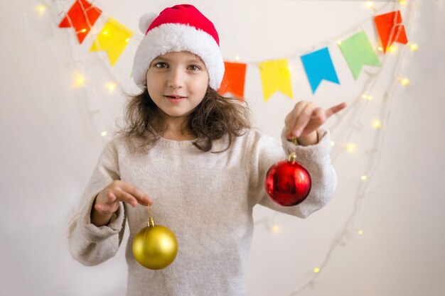 Menina com boné de Natal segurando bolas de Natal e sorrisos