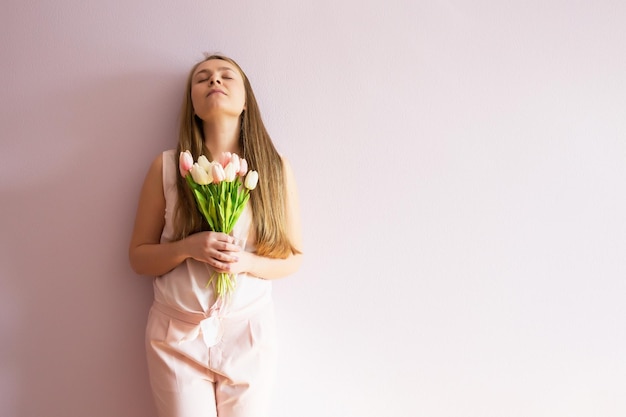 menina com cabelo comprido loiro dissolvido um chapéu de feltro na cabeça mantém flores da primavera nas mãos