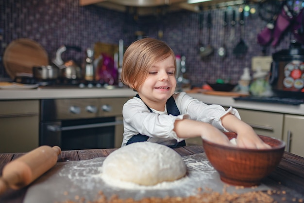 Menina com cabelo curto, amassar massa na cozinha