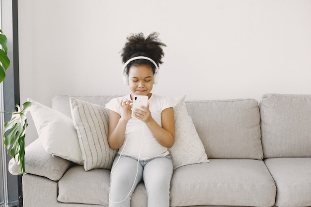 Menina com cabelo encaracolado. criança seca música em fones de ouvido. divirta-se em casa.