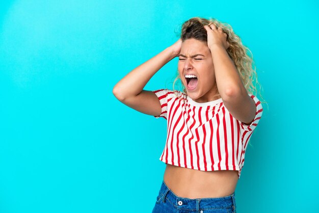 Menina com cabelo encaracolado isolado em um fundo azul estressada oprimida