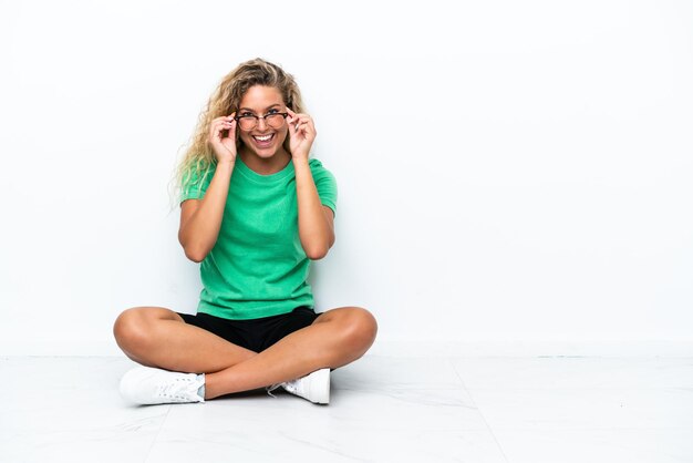 Menina com cabelo encaracolado, sentada no chão com óculos e surpreso