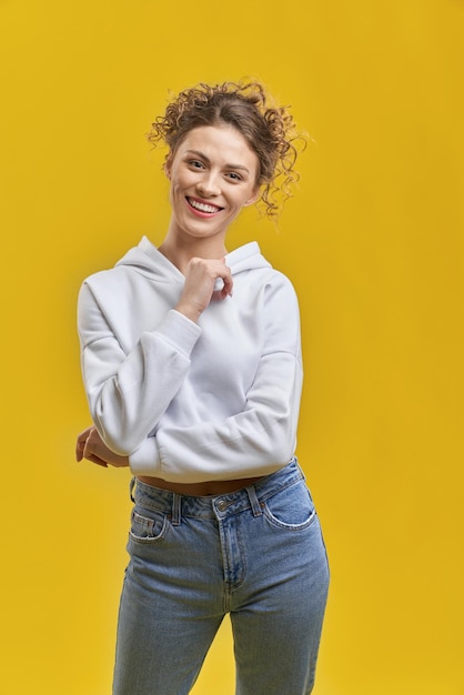 Menina com cabelo encaracolado sorrindo levantando a mão no queixo