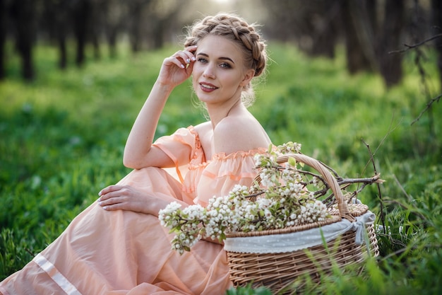 Menina com cabelo loiro em um vestido leve no jardim florido. conceito de moda feminina primavera.